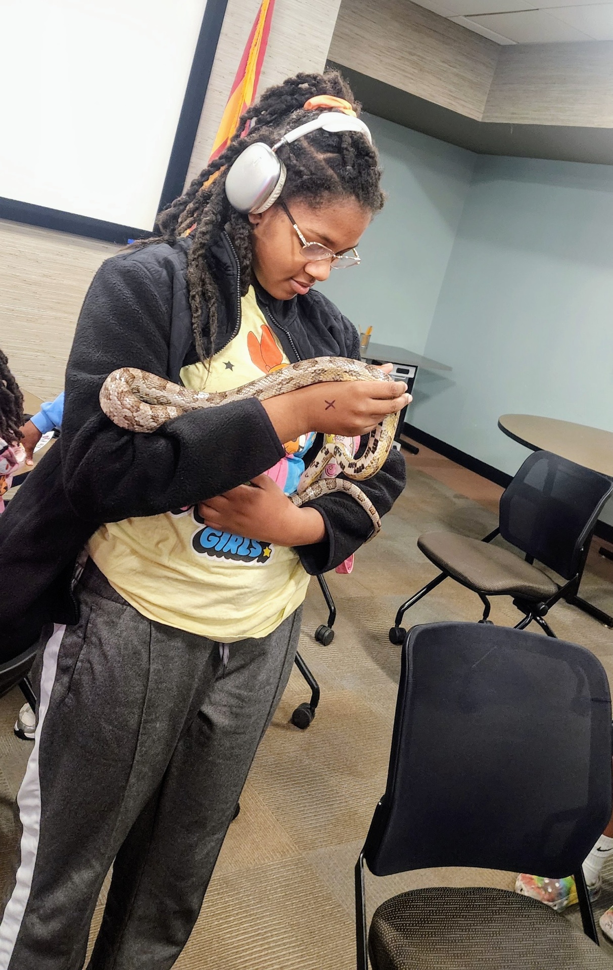 A student gently cradling a corn snake with focused curiosity.